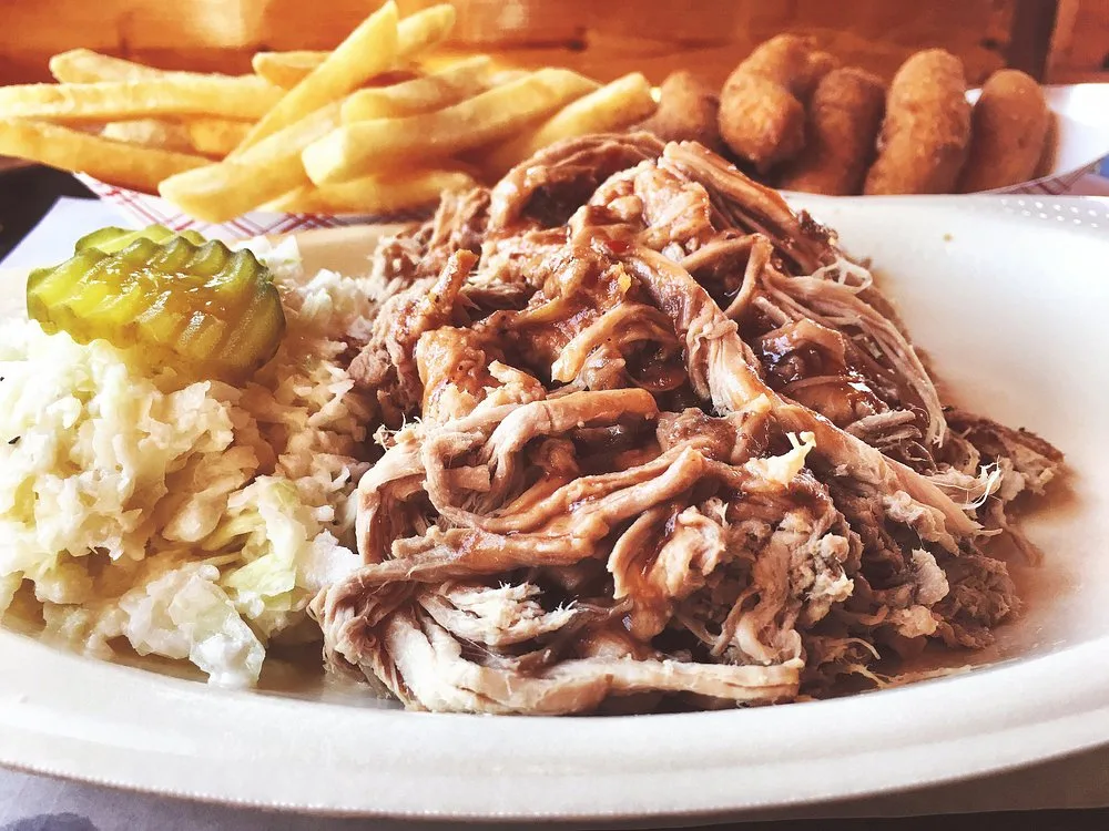 Pit-smoked pulled pork BBQ plate with red slaw, fries, and hushpuppies