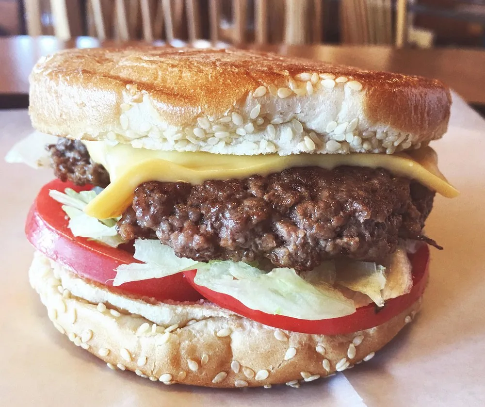 Cheeseburger King sandwich with melted cheese, lettuce, and tomato on a toasted sesame bun