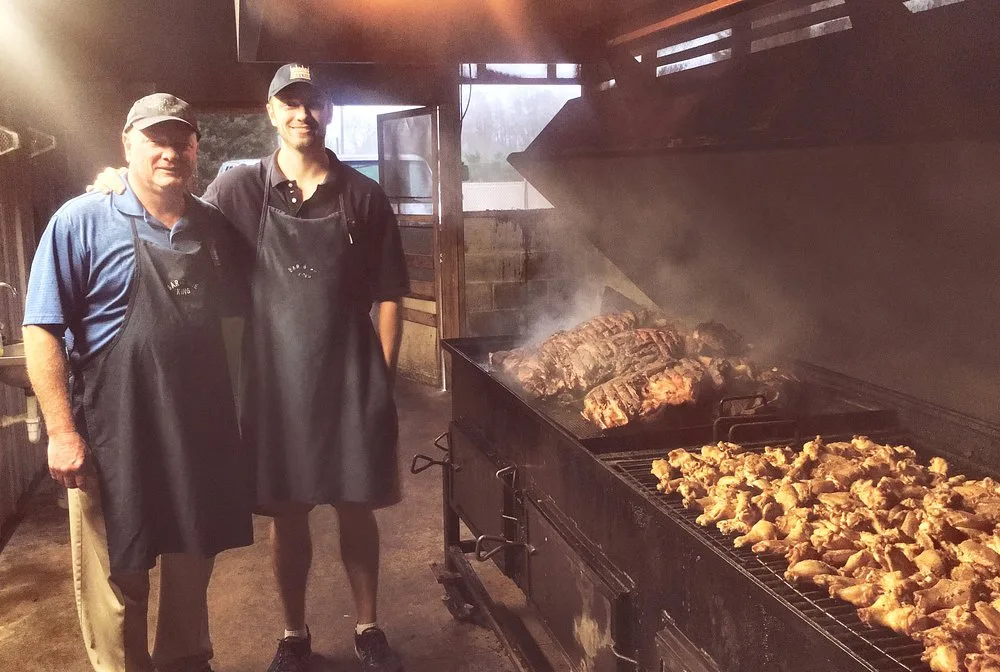 Keith Smith and his son Jordan standing together in front of the smoking pit