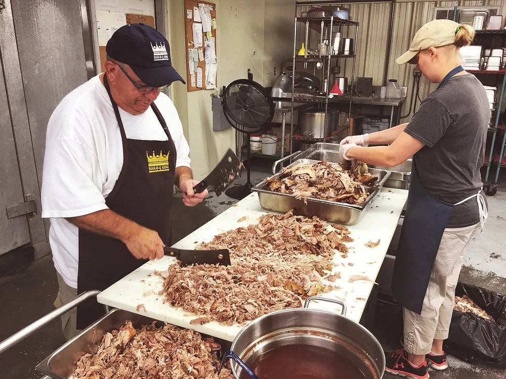 Keith Smith and an employee chopping pork shoulder together at the prep table in the walk-in cooler area