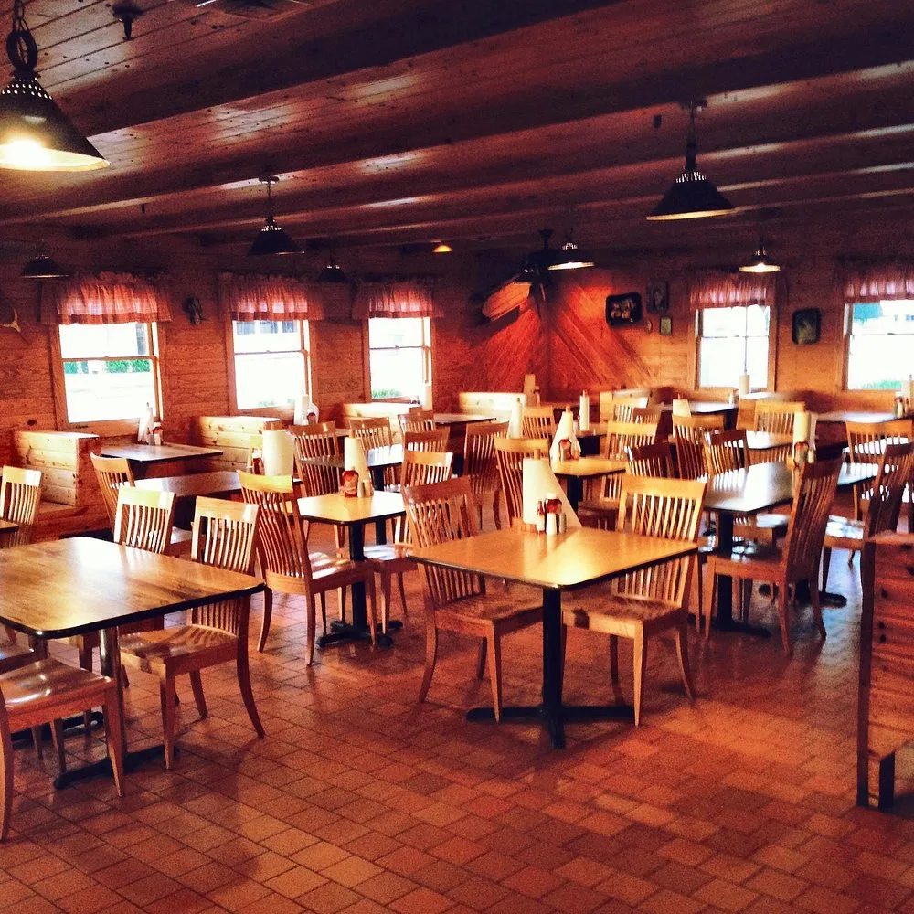 Bar-B-Q King's log-cabin-style dining room with wooden tables, chairs, and beamed ceiling before opening