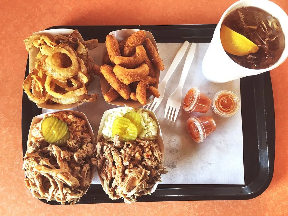 Hand-breaded onion rings and golden hushpuppies served with sweet tea and sauce cups