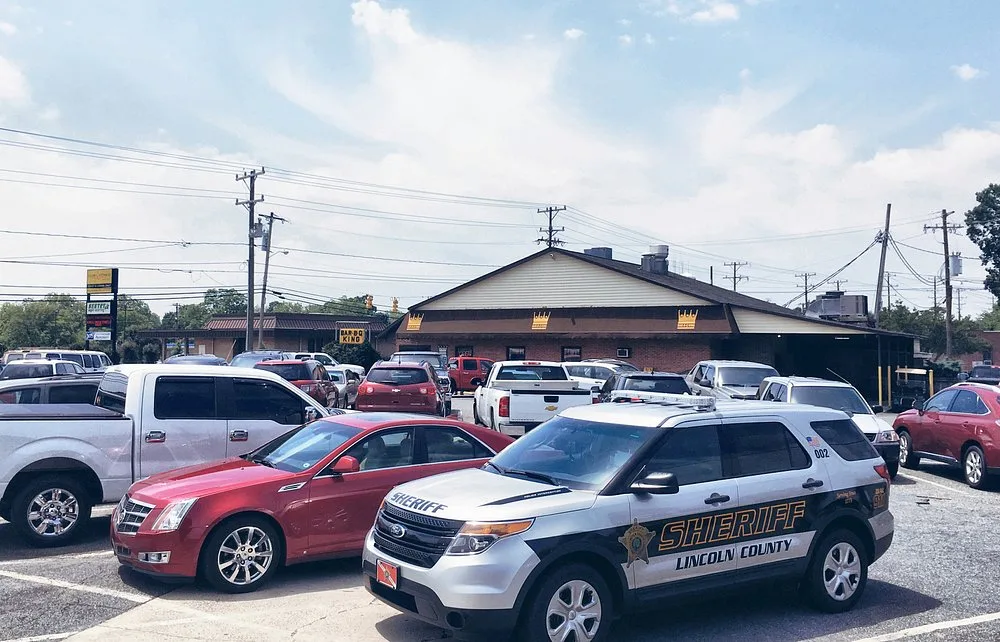 Bar-B-Q King parking lot with a Lincoln County Sheriff vehicle among customer cars on a sunny day