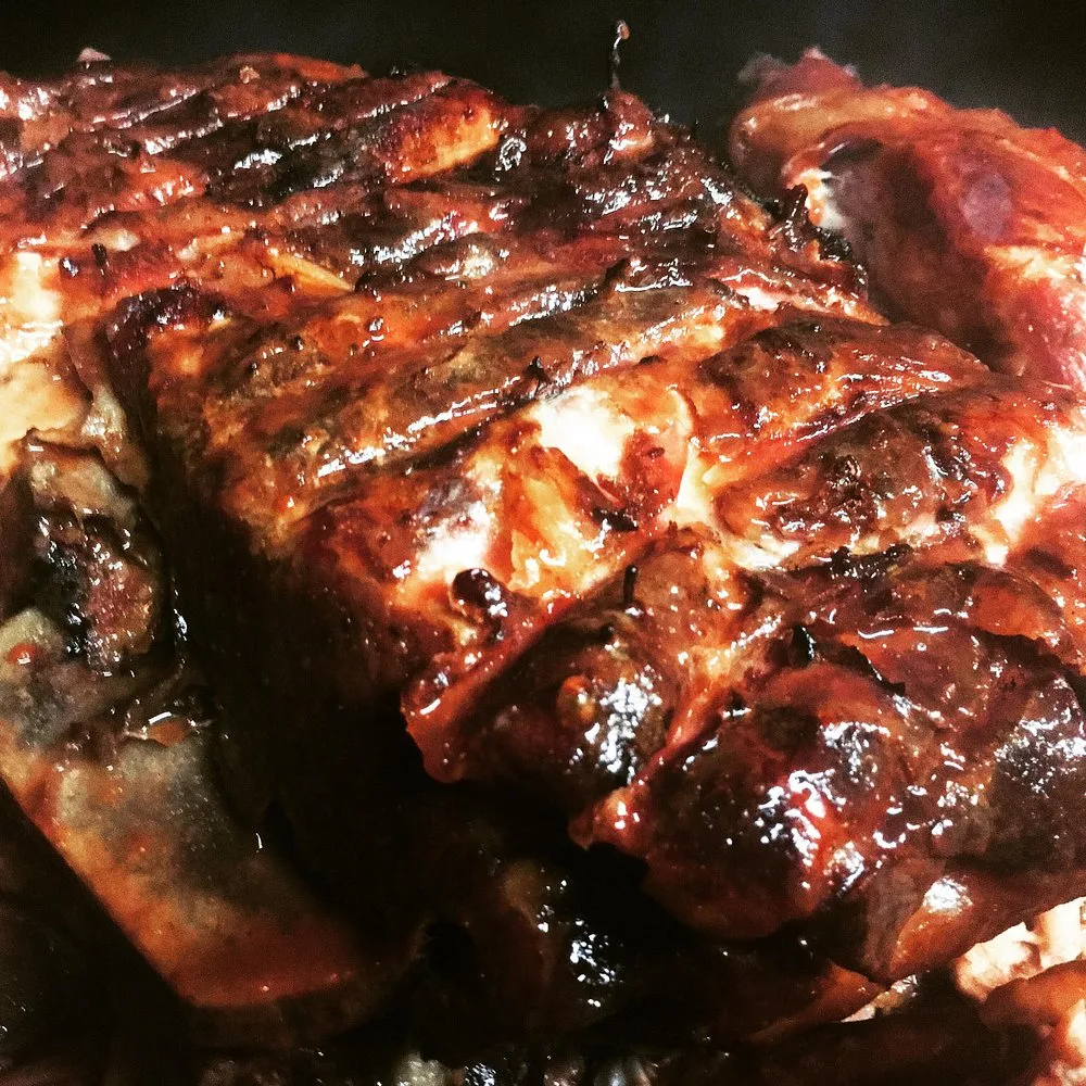 Macro shot of a whole pit-smoked pork shoulder with a dark caramelized bark