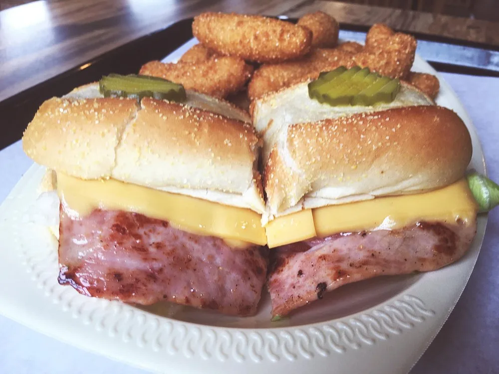 Poor Boy ham and cheese sandwich on a sub roll with pickles, served with a side of hushpuppies