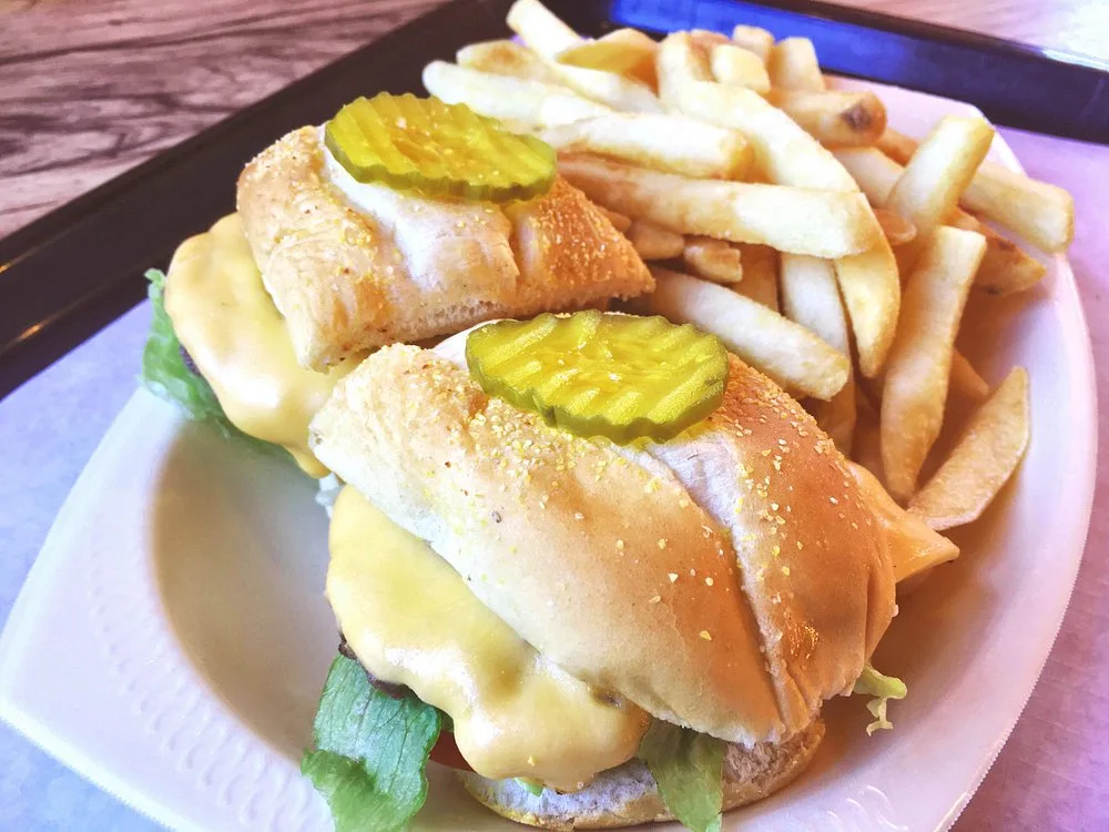 Poor Girl sandwiches with melted cheese and pickles served with a side of crispy fries