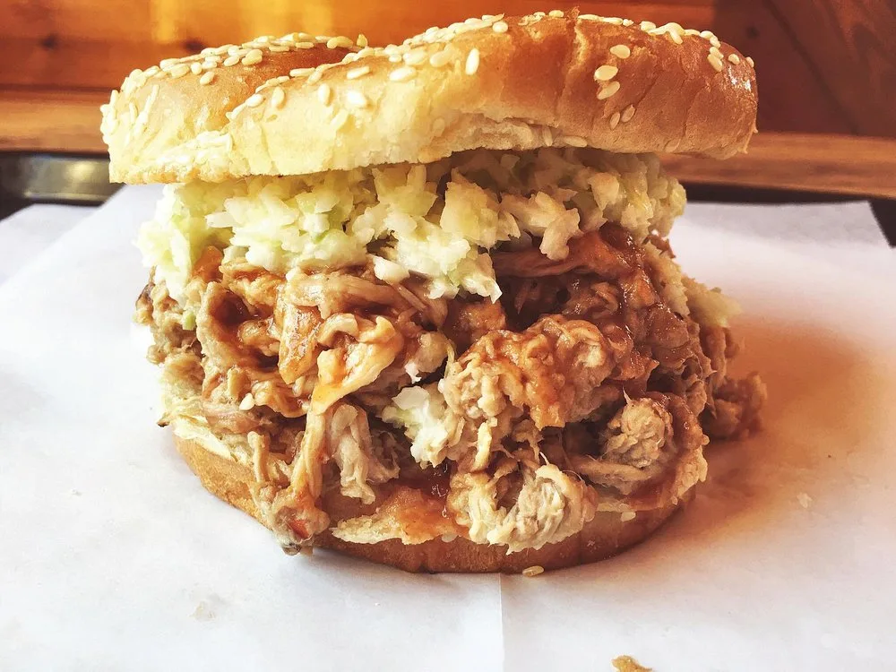 Close-up of a toasted BBQ sandwich piled high with pulled pork and coleslaw