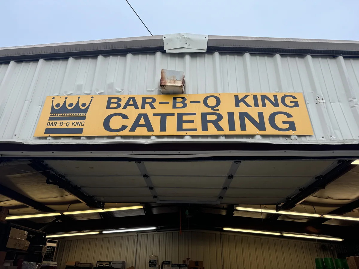 The yellow Bar-B-Q King Catering sign above the smoke pit's open garage bay