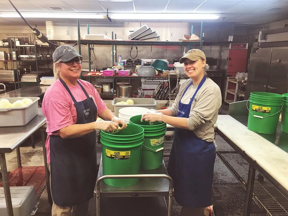 BBQ King employees packing dill pickle chips into buckets in the prep kitchen